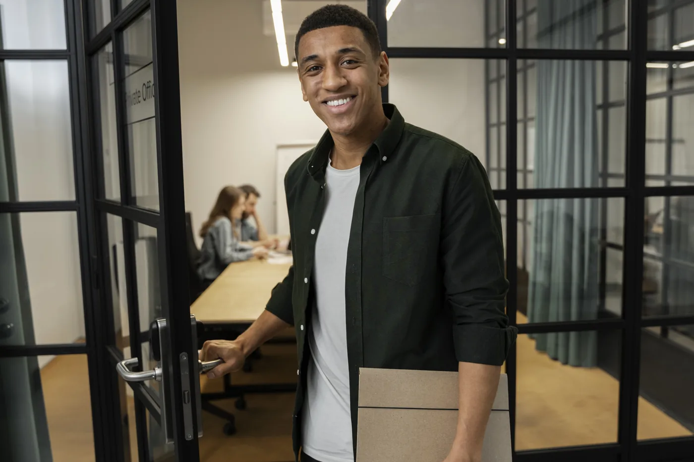 Apprenant en alternance souriant à l'entrée d'une salle de réunion en entreprise